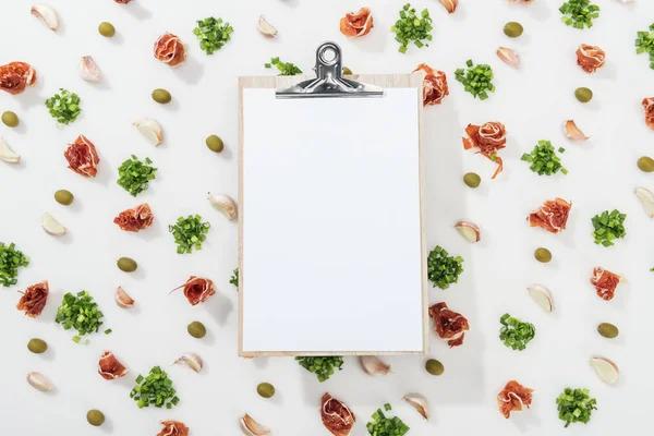 Top view of clipboard among prosciutto, olives, garlic cloves and greenery — Stock Photo