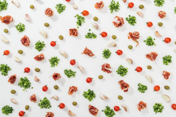 Top view of prosciutto, olives, garlic cloves, greenery and cherry tomatoes — Stock Photo