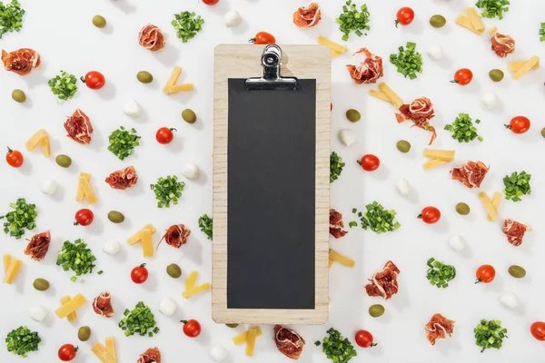 Prancheta em branco com letras de menu entre azeitonas, prosciutto, verdura, mussarela, queijo cortado e tomate cereja — Fotografia de Stock