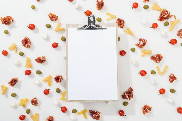 White clipboard among olives, prosciutto, mozzarella, cut cheese and cherry tomatoes — Stock Photo