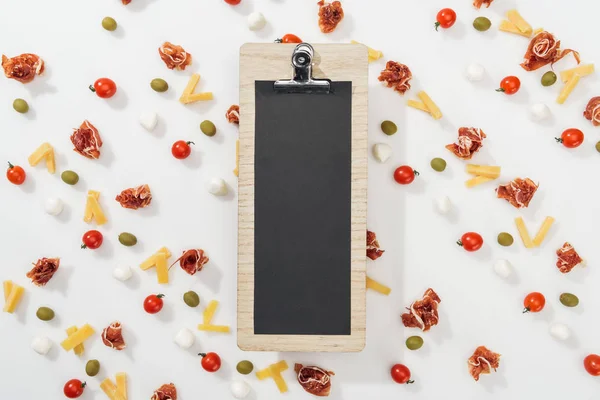 Black clipboard among olives, prosciutto, mozzarella, cut cheese and cherry tomatoes — Stock Photo