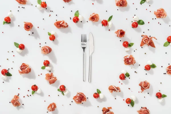 Plat couche de fourchette et couteau près de savoureux aliments biologiques sur fond blanc — Stock Photo