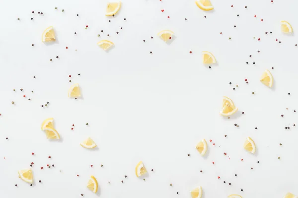 Tendido plano de rodajas de limón cerca de granos de pimienta roja y negra aislados en blanco - foto de stock