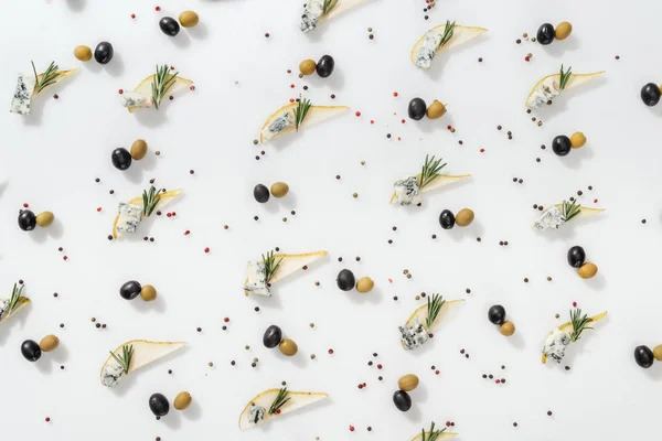 Flat lay of sliced pears with blue cheese and rosemary twigs near black and green olives on white background — Stock Photo