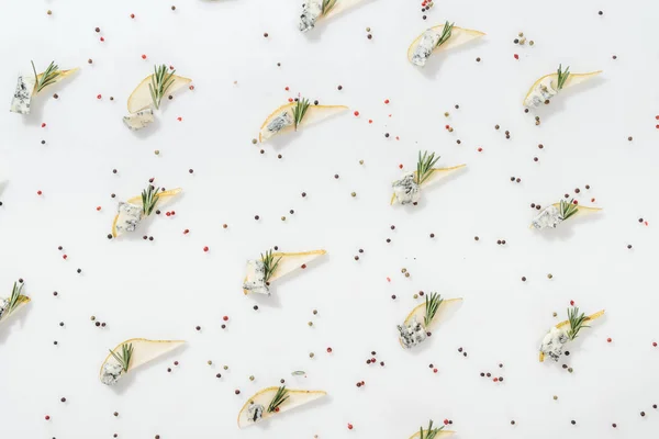 Top view of sliced pears with blue cheese and rosemary twigs near black and red peppercorns isolated on white — Stock Photo