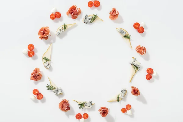 Top view of sliced pears with blue cheese and rosemary twigs near tasty prosciutto, cherry tomatoes and mozzarella cheese on white background — Stock Photo