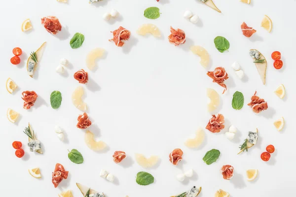 Couche plate de prosciutto savoureux près des ananas tranchés et des ingrédients sains sur fond blanc — Photo de stock