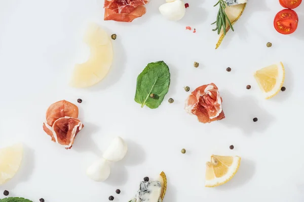 Disposición plana de delicioso prosciutto cerca de ingredientes frescos y especias sobre fondo blanco - foto de stock