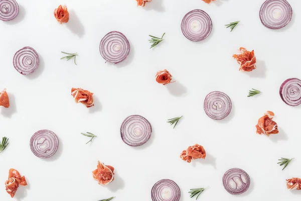 Flache Lage roter Zwiebelringe in der Nähe von schmackhaftem Schinken und Rosmarinzweigen auf weißem Hintergrund — Stockfoto