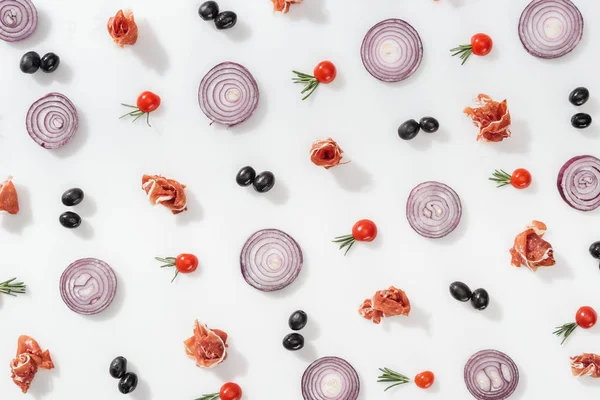 Flat lay of red onion rings near tasty prosciutto, cherry tomatoes, rosemary twigs and black olives on white background — Stock Photo