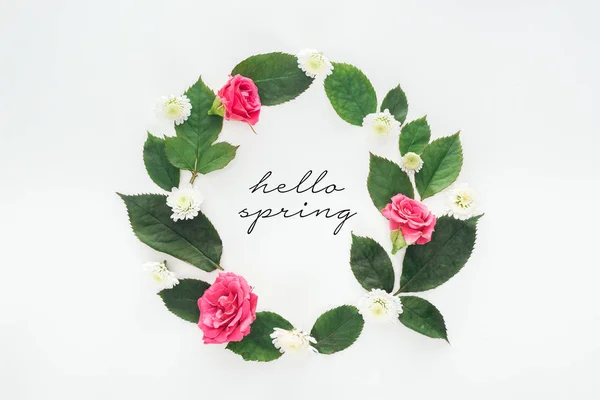 Vista superior de composición circular con hojas verdes, rosas y crisantemos sobre fondo blanco con ilustración de primavera hola - foto de stock