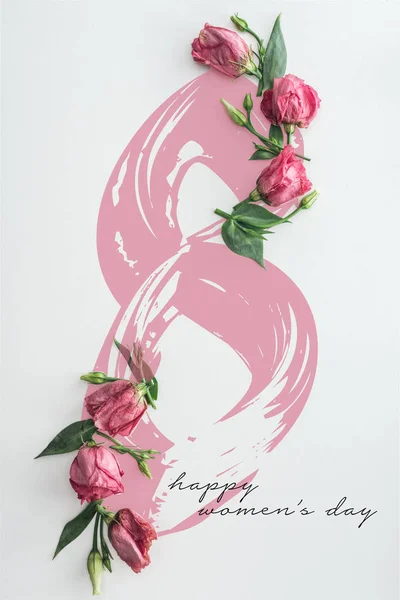 Vista superior de rosas rosadas sobre fondo blanco con letras felices del día de las mujeres - foto de stock