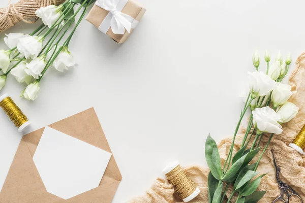 Vue du dessus de l'eustomie, cadeau enveloppé, enveloppe avec carte vide, ciseaux et tissu sur fond gris — Photo de stock