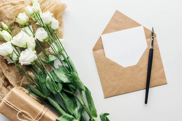 Draufsicht auf Eustoma, Umschlag mit leerer Karte, verpacktes Geschenk, Tuch und Tuschstift auf grauem Hintergrund — Stockfoto