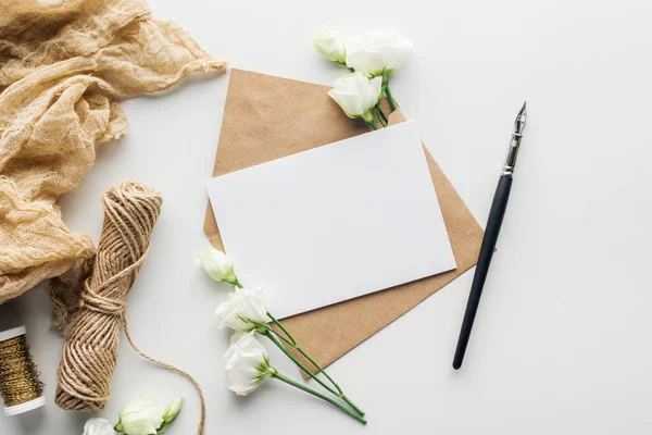 Vista superior de eustoma, pano, envelope com cartão vazio e caneta de tinta sobre fundo cinza — Fotografia de Stock