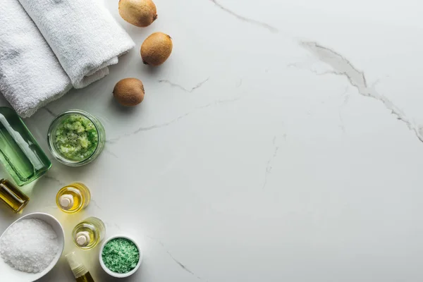 Vista superior de ingredientes naturales para cosméticos hechos a mano, toallas y botellas en superficie blanca - foto de stock