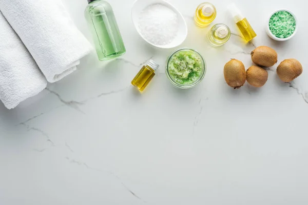 Vista dall'alto di bottiglie cosmetiche, asciugamani e vari componenti per cosmetici fatti in casa su superficie bianca — Foto stock