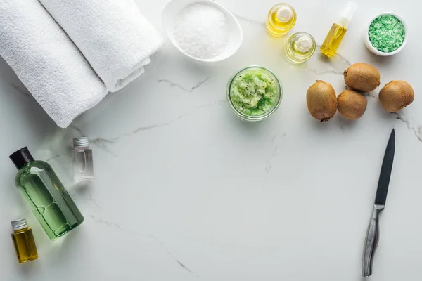 Vista superior de diferentes ingredientes para la fabricación de cosméticos, toallas y botellas de cosméticos en la superficie blanca - foto de stock