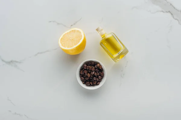 Vista superior da tigela com grãos de café, meio limão e garrafa de suco de limão na superfície branca — Fotografia de Stock