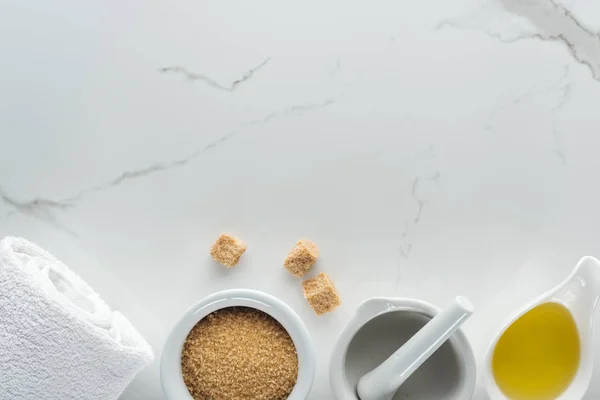 Top view of bowls with natural ingredients for handmade cosmetics, pounder and towel on white surface — Stock Photo