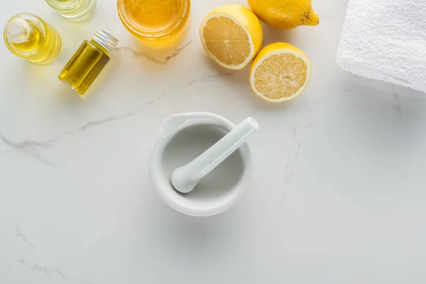 Vista superior de limones, chorro de agua y varios ingredientes naturales para la fabricación de cosméticos en la superficie blanca - foto de stock