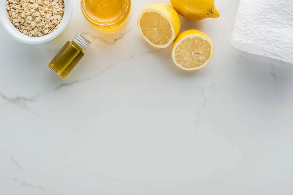 Vista superior de limones, miel, copos de avena y varios ingredientes para la fabricación de cosméticos en la superficie blanca - foto de stock