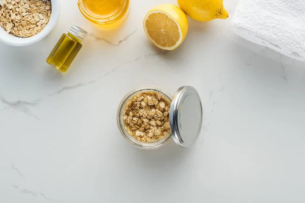 Vista superior del recipiente de vidrio con mezcla de copos de avena y miel en la superficie blanca - foto de stock