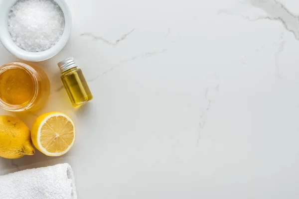 Vista superior de limones, miel, sal y otros ingredientes naturales para cosméticos hechos a mano en superficie blanca - foto de stock
