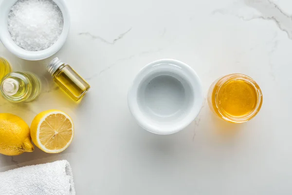 Vista dall'alto di limoni e ciotole con ingredienti diversi per cosmetici fatti in casa su superficie bianca — Foto stock
