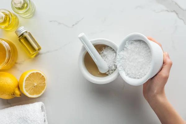 Partial view of woman pouring salt into pounder on white surface — Stock Photo