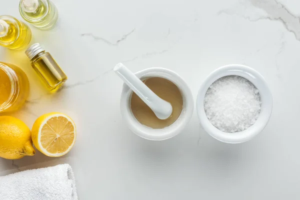 Vista superior de pounder, tigela com sal, e vários componentes naturais para cosméticos caseiros na superfície branca — Fotografia de Stock