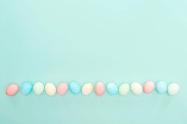 Vista superior de los huevos tradicionales de Pascua en fila aislados en azul - foto de stock