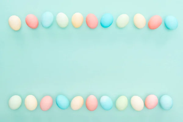 Vue de dessus des œufs de Pâques pastel traditionnels en rangées isolées sur bleu — Photo de stock