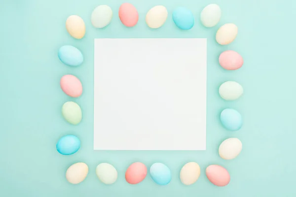 Top view of traditional pastel easter eggs near greeting card isolated on blue — Stock Photo