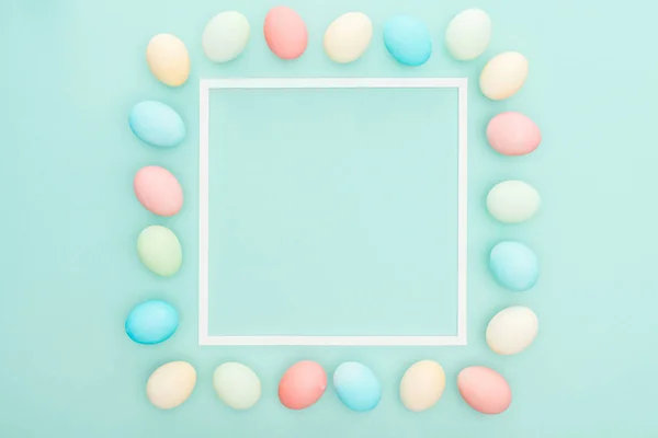 Top view of pastel easter eggs near empty frame isolated on blue — Stock Photo