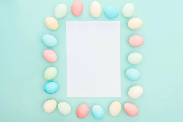 Top view of pastel easter eggs near blank card isolated on blue — Stock Photo