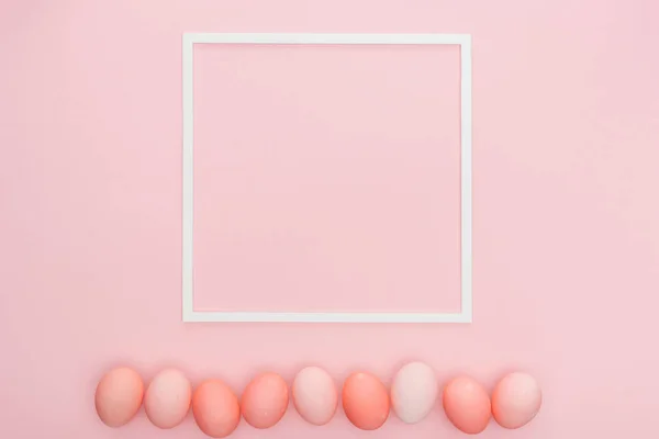 Vue de dessus des œufs de Pâques pastel traditionnels avec cadre vide isolé sur rose — Photo de stock