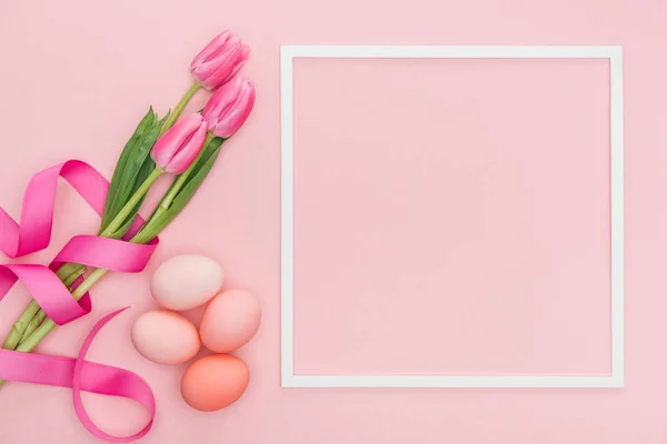 Vue de dessus des tulipes roses et des œufs de Pâques avec cadre isolé sur rose — Photo de stock