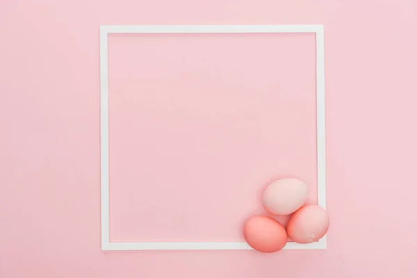 Top view of pastel easter eggs with empty frame isolated on pink — Stock Photo