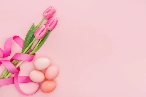 Top view of pink tulips with ribbon and easter eggs isolated on pink — Stock Photo