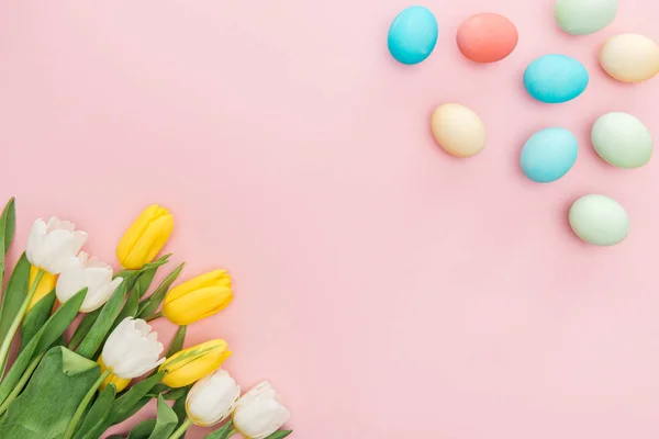 Vista superior de flores de tulipán y huevos tradicionales de Pascua aislados en rosa - foto de stock