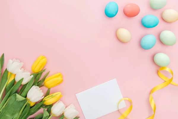 Top view of empty greeting card with tulips and easter eggs isolated on pink — Stock Photo