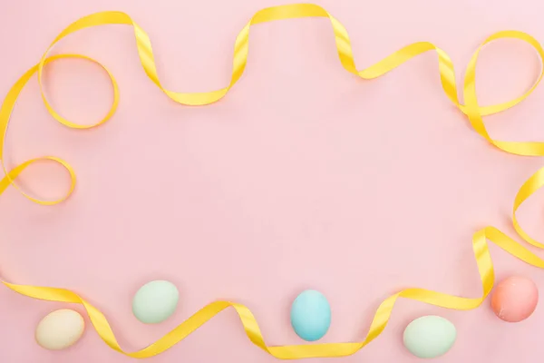 Vista superior de la cinta y los huevos tradicionales de Pascua aislados en rosa - foto de stock