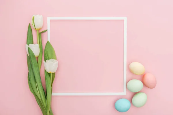 Top view of frame with tulips and pastel easter eggs isolated on pink — Stock Photo