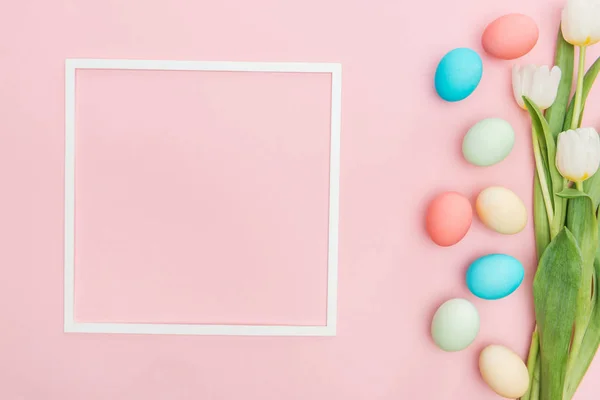 Top view of tulips and pastel easter eggs with frame isolated on pink — Stock Photo