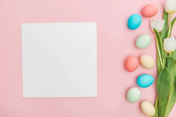 Vue du dessus des tulipes et des œufs de Pâques au pastel isolés sur du rose avec planche vide — Photo de stock