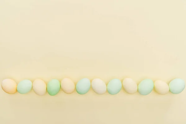 Uova pasquali pastello tradizionali in fila isolate su giallo — Foto stock