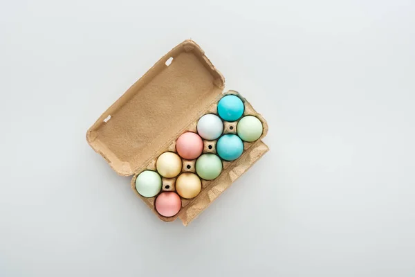Top view of pastel easter eggs in paper container isolated on grey — Stock Photo