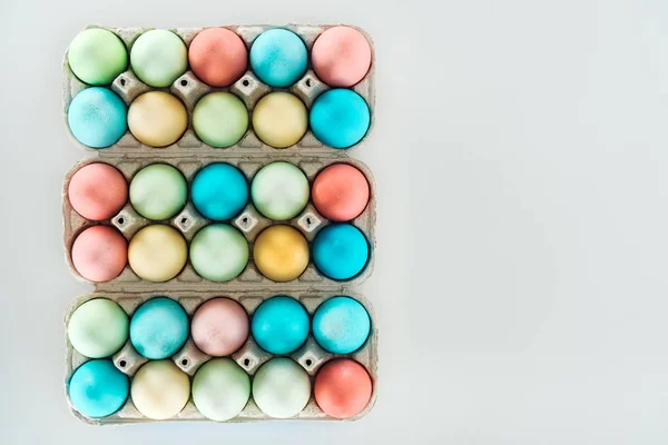 Top view of pastel easter eggs in paper containers isolated on grey — Stock Photo