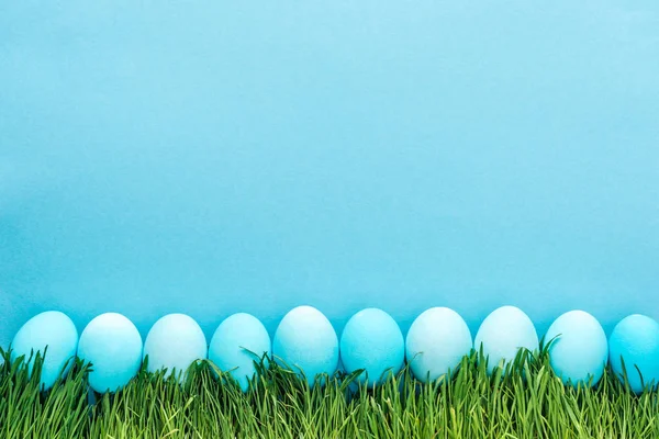 Top view of traditional easter eggs on grass isolated on blue — Stock Photo